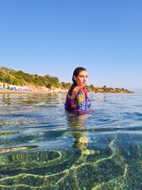 Portrait of woman swimming in sea against clear sky