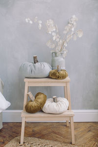 Flower vase and pumpkins on table against wall at home