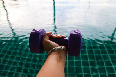 Low section of woman holding hands in swimming pool