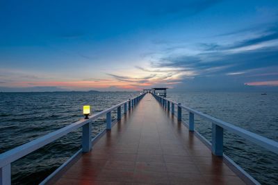 Pier over sea against sky during sunset