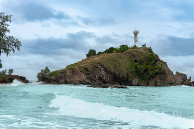 Lighthouse by sea against sky