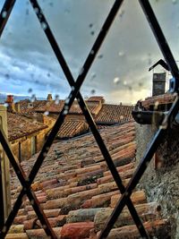 Buildings against sky seen through chainlink fence