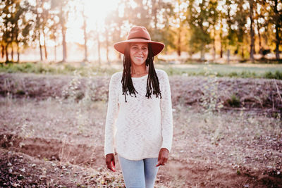 Full length portrait of smiling woman standing on land