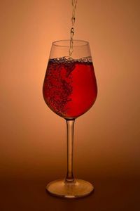 Close-up of red wine in wineglass against orange background