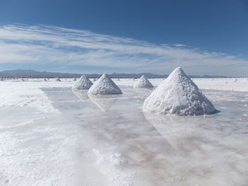 Salt heap at salar de uyuni against sky