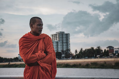 Man standing at riverbank against sky