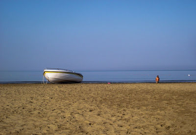 Deck chairs on beach against clear sky
