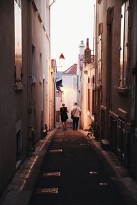 Rear view of people walking on street amidst buildings in city