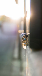Close-up of key hanging on metal during sunset