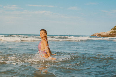 Portrait of young woman standing in sea against sky