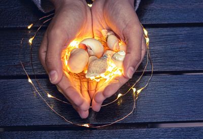 Midsection of person holding illuminated candles