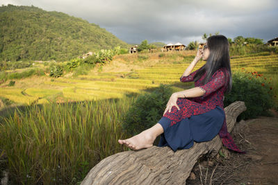 Rear view of woman sitting on field