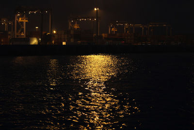 Illuminated city by sea at night
