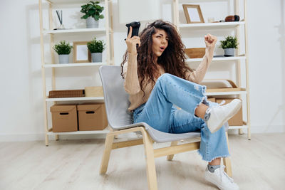 Young woman using mobile phone while sitting on sofa at home