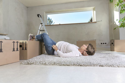 Pregnant woman lying on carpet at home