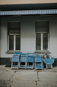Empty chairs and tables against building