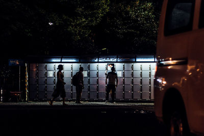 People by illuminated lockers at night