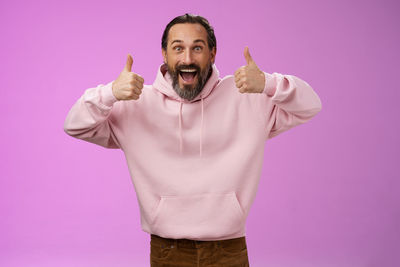 Portrait of man standing against pink background