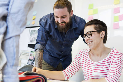 Happy business people discussing over samples at desk in creative office