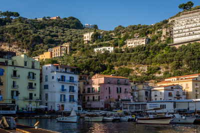 Boats moored on sea against buildings at sorrento