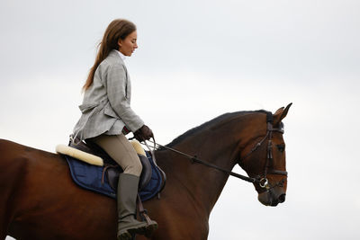 Woman riding horse against sky