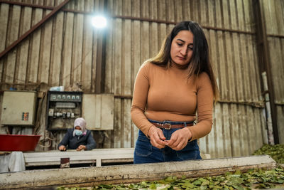 Portrait of young woman standing against wall