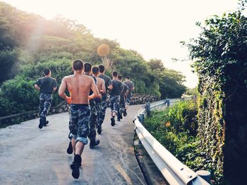 Rear view of people walking on road against trees