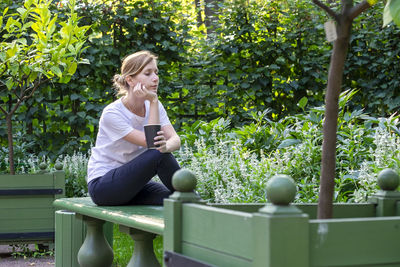 Rear view of woman sitting on mobile phone