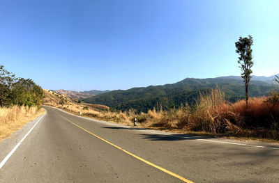 Road by mountains against clear sky