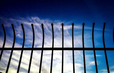 Low angle view of fence against blue sky