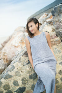 Portrait of smiling young woman standing on rock