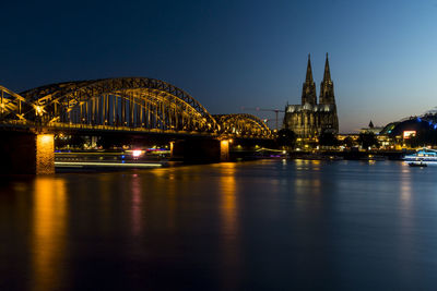Illuminated bridge over river at night