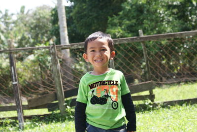 Portrait of smiling boy holding fence