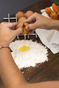 Cropped hands of woman mixing egg with flour on table