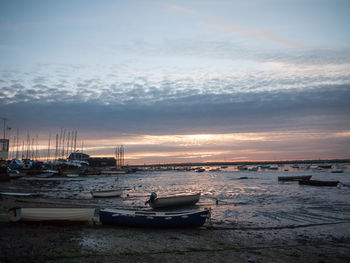 Boats moored at harbor against sky during sunset