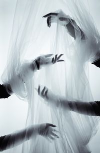 Cropped hands of women wrapped in plastics against white background