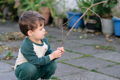 Boy playing with a stick in the garden