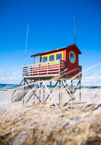 Lifeguard hut on beach against clear blue sky