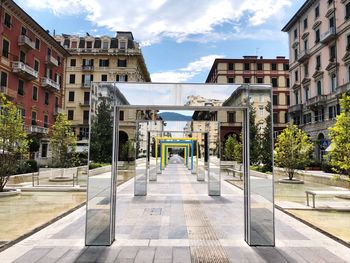 Footpath amidst buildings in city against sky