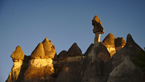 Low angle view of rocks against clear blue sky