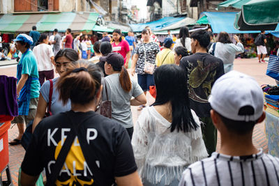 Rear view of people walking on city street