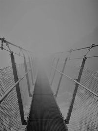 Footbridge against clear sky during foggy weather