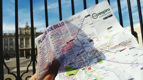 Cropped image of hand holding map against gate