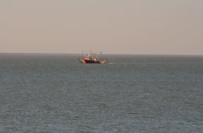 Boat sailing in sea against clear sky