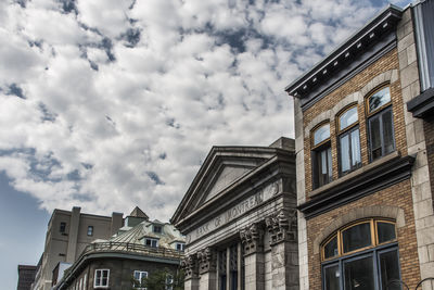 Low angle view of buildings against cloudy sky