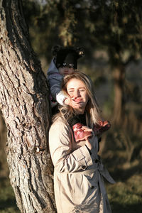 Young woman standing by tree trunk