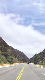 Road leading towards mountains against sky