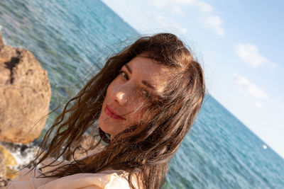Close-up portrait of woman at beach against sky