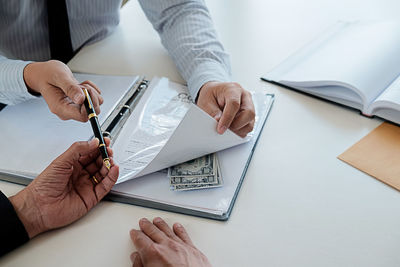 Midsection of man holding paper at table