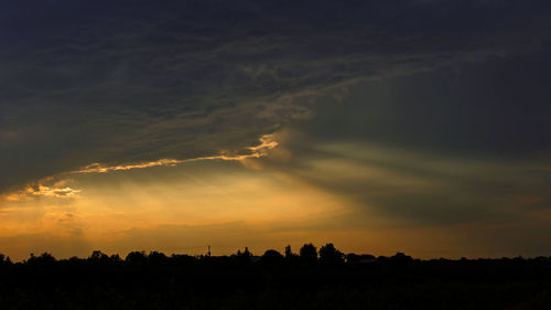 Silhouette landscape against dramatic sky during sunset